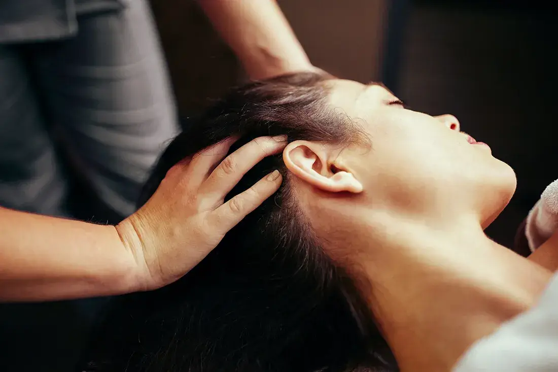 Hands supporting the neck and back of the head during massage.