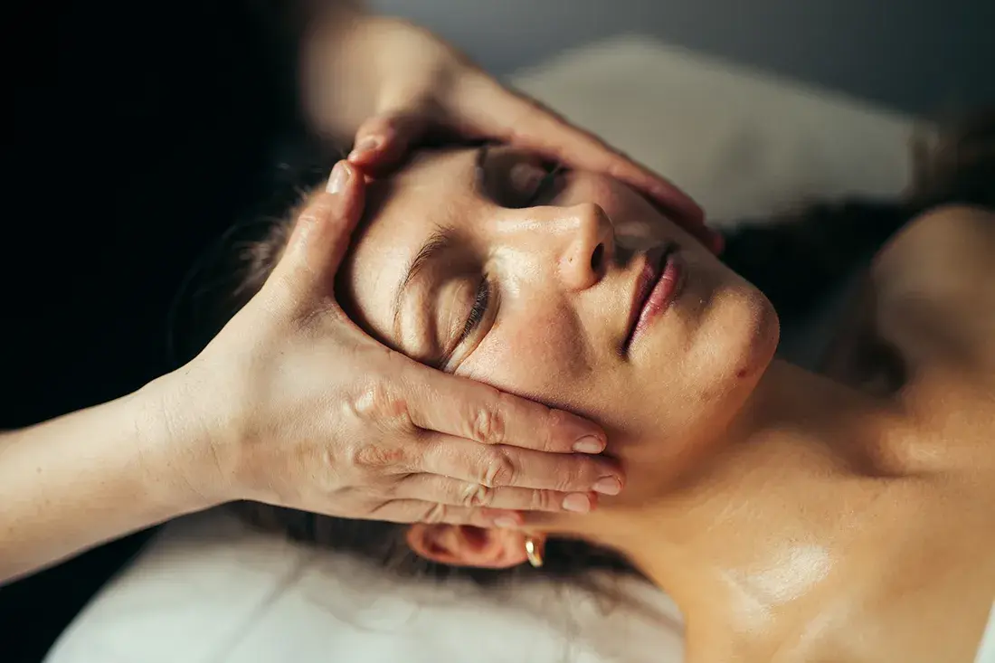 Hænder omkring kinderne under en manuel ansigtsmassage.