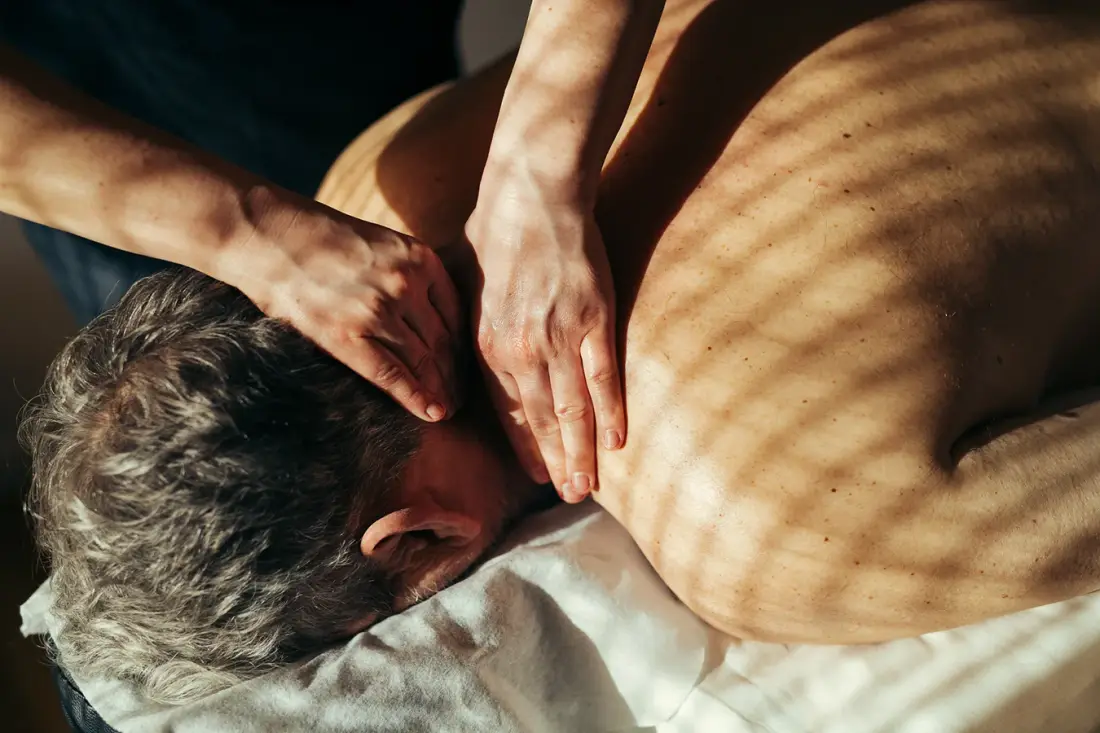 Rolig rygmassage i behandlingsrummets varme lys.