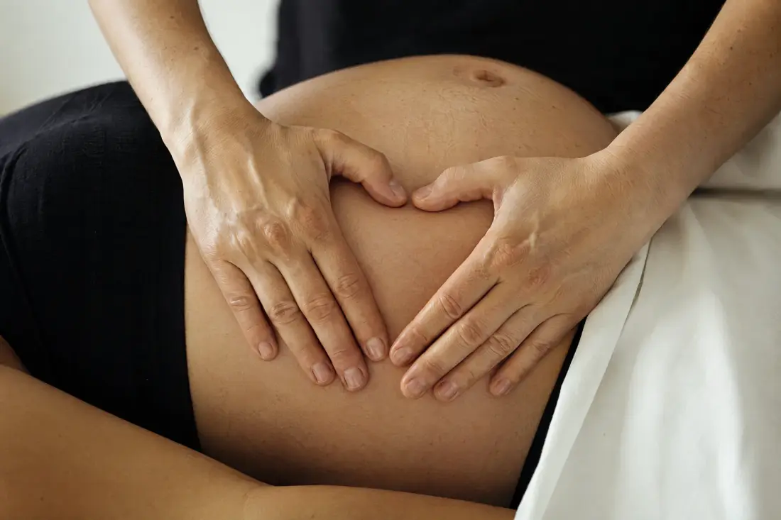 Hænder, der hviler på en gravid mave.