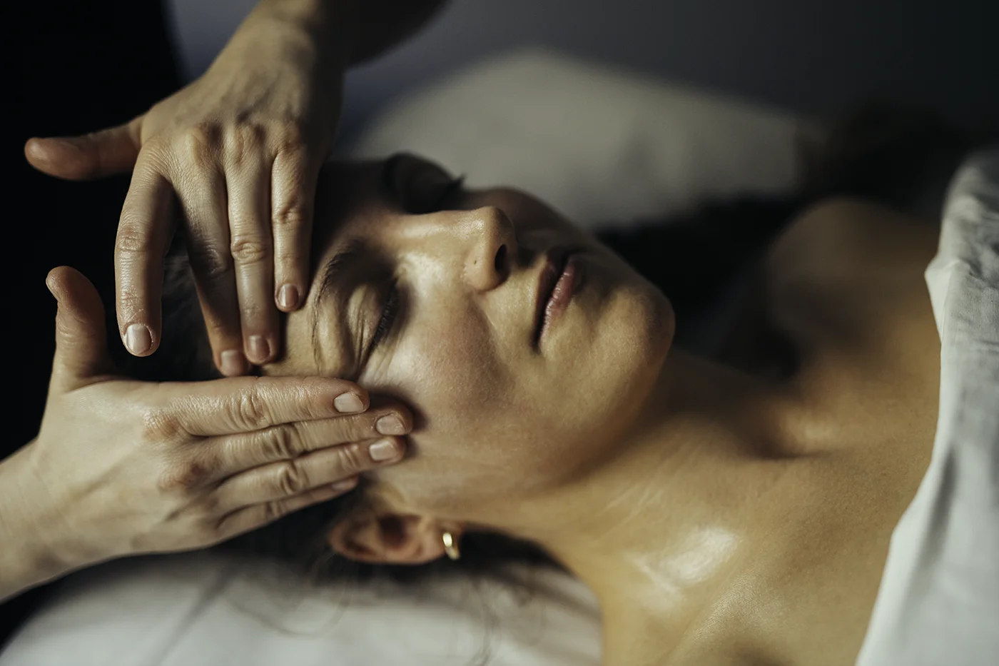 Massørens hænder udfører japansk lifting ansigtsbehandling